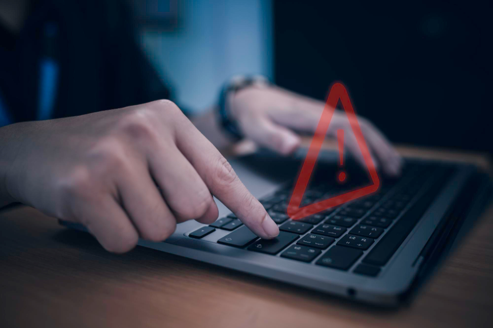 Two hands touching keyboard with a warning sign