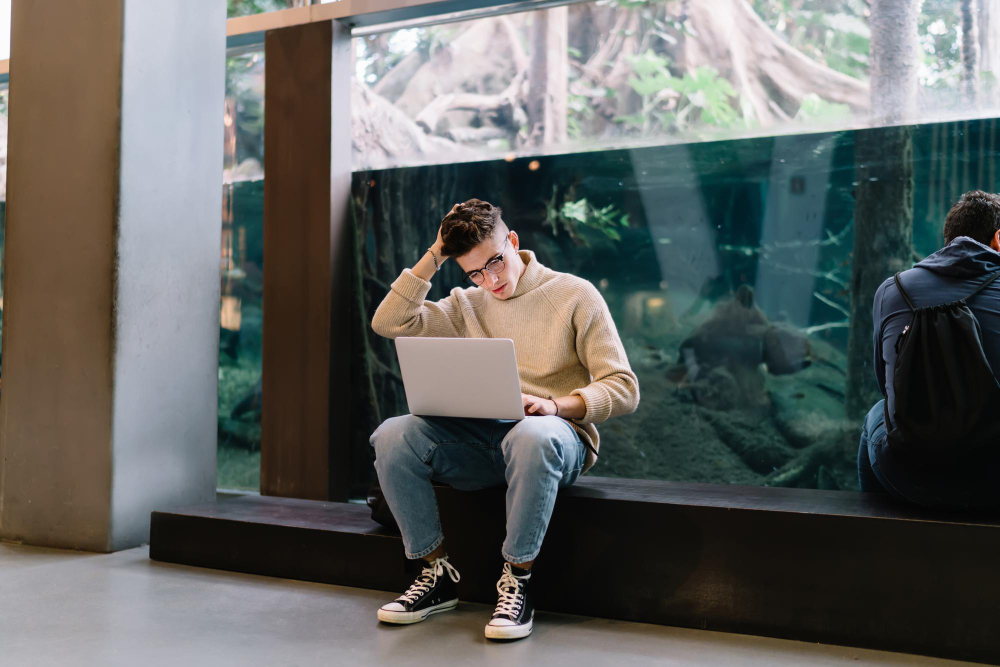 A man with a laptop in hallway wondering why his laptop is running slow